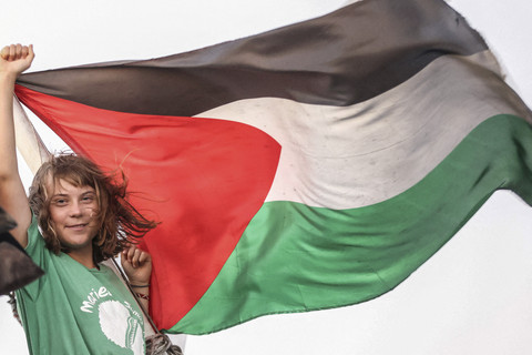 Aktivis lingkungan asal Swedia, Greta Thunberg mengibarkan bendera Palestina saat berlayar bersama Global Sumud Flotilla menembus blokade laut Israel untuk mengirimkan bantuan kemanusiaan ke Gaza di Yunani, Kamis (25/9/2025). Foto: Stefanos Rapanis/Reuters