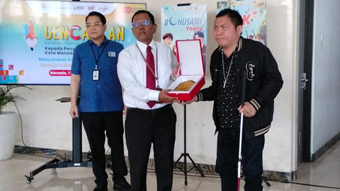 Penyerahan piagam dari OJK SulutgoMalut ke perwakilan Disabilitas di Sulawesi Utara pada kegiatan sosialisasi layanan jasa keuangan kepada seratus orang penyandang disabilitas.