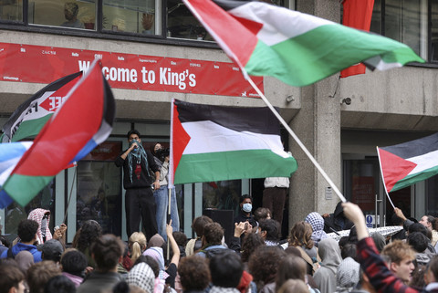 Para pengunjuk rasa mengibarkan bendera saat mahasiswa berpartisipasi dalam hari peringatan dua tahun serangan Hamas terhadap Israel, i kampus King's College London, Inggris, Selasa (7/10/2025). Foto: Toby Melville/REUTERS