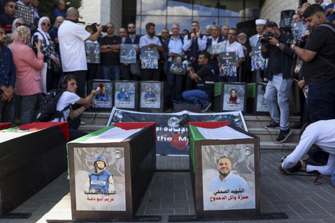 Para jurnalis Palestina dan pejabat lokal berkumpul di sekitar peti mati simbolis dan potret para pekerja media yang tewas dalam tembakan Israel dalam rangka memperingati dua tahun perang Gaza di kota Ramallah, Tepi Barat Palestina, Rabu (8/10/2025). Foto: Zain Jaafar/AFP