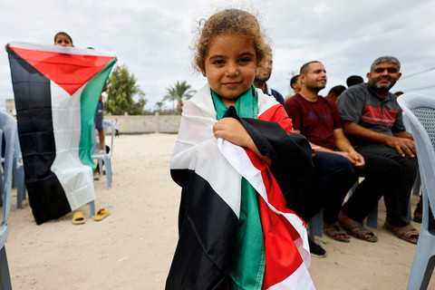 Seorang gadis memegang bendera Palestina usai pengumuman gancatan senjata fase pertama Israel dan Hamas di Jalur Gaza tengah, Kamis (9/10/2025). Foto: Mahmoud Issa/REUTERS