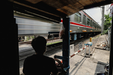 Warga berjaga saat kereta Commuter Line melintas di dekat palang perlintasan rel kereta api sebidang di kawasan Tebet Timur, Jakarta, Sabtu (11/10/2025). Foto: Darryl Ramadhan/kumparan