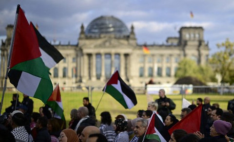 Sejumlah massa membawa bendera Palestina, dalam demonstrasi yang digelar di depan gedung parlemen Jerman, Reichstag, di Berlin, Sabtu (11/10).  Foto: Tobias Schwarz/AFP