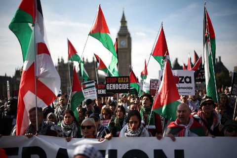Sejumlah masyarakat menggelar aksi massa di London, mereka membawa bendera Palestina dan plakat 'Stop Gaza Genocide', Sabtu (11/10). Foto: Henry Nicholls/AFP
