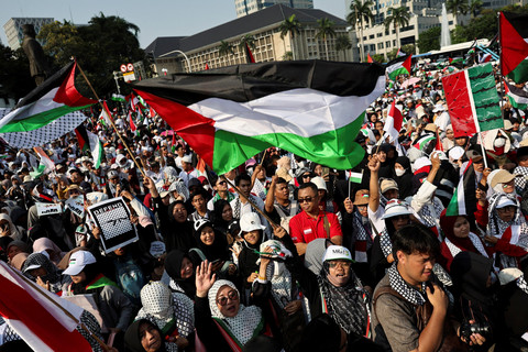 Massa mengibarkan bendera Palestina saat mengikuti Aksi Bela Palestina di Kawasan Patung Kuda, Jakarta, Minggu (12/10/2025). Foto: Willy Kurniawan/REUTERS