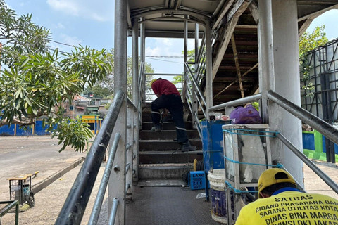 Petugas memperbaiki jembatan penyeberangan orang (JPO) Halte Transjakarta Kramat Jati, Jakarta, Minggu (12/10/2025). Foto: Abid Raihan/kumparan