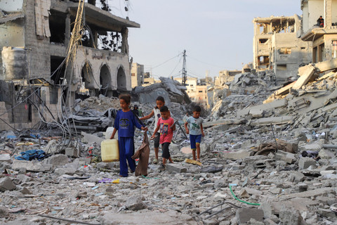 Warga berjalan di tengah kehancuran di Kota Gaza, Jalur Gaza utara, Minggu (12/10/2025). Foto: Ebrahim Hajjaj/REUTERS