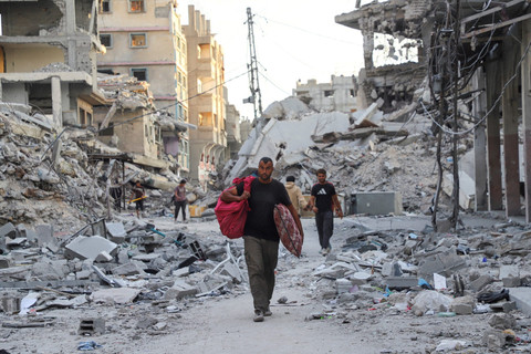 Warga berjalan di tengah kehancuran di Kota Gaza, Jalur Gaza utara, Minggu (12/10/2025). Foto: Ebrahim Hajjaj/REUTERS