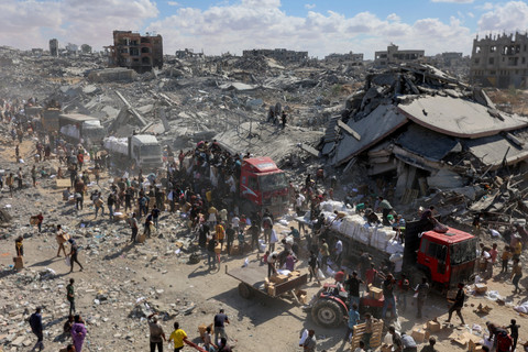 Warga Palestina berebut bantuan dari truk bantuan yang masuk dari perlintasan Karem Abu Salem, di Khan Yunis, Jalur Gaza selatan, Minggu (12/10/2025). Foto: Omar AL-QATTAA / AFP