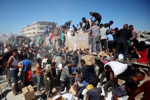Warga Palestina berebut bantuan dari truk bantuan yang masuk dari perlintasan Karem Abu Salem, di Khan Yunis, Jalur Gaza selatan, Minggu (12/10/2025). Foto: Omar AL-QATTAA / AFP