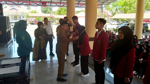 Bupati Bolmong, Yusra Alhabsyi, menyematkan tanda peserta kepada mahasiswa IKTGM yang akan mengikuti KKN Berdampak di wilayah Kabupaten Bolmong.
