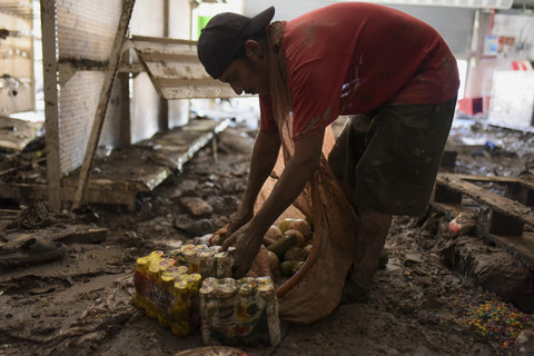 Warga berjalan menyelamatkan minuman dalam botol dari lantai berlumpur usai banjir di salah satu supermarket di Alamo, negara bagian Veracruz, Meksiko, Senin (13/9/2025).  Foto: Rolando Ramos/Reuters