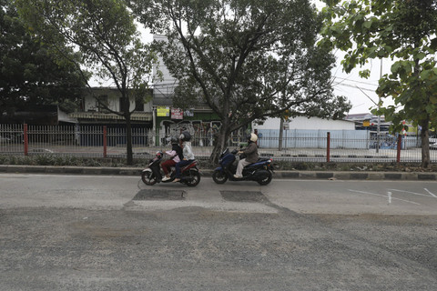 Dua pengendara sepeda motor melintas di dekat jalan rusak di kawasan Kramat Jati, Jakarta Timur, Rabu (15/10/2025). Foto: Jamal Ramadhan/kumparan
