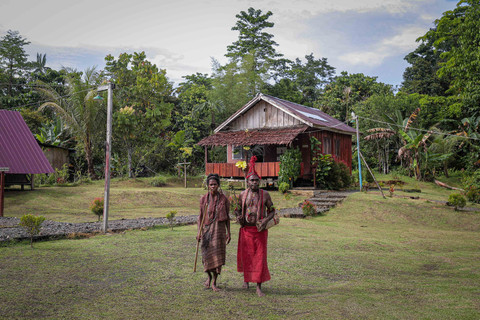 Mama dan Bapak suku Moi Kelim berdiri di antara bangunan yang ada di Kampung Adat Malasigi, Papua Barat Daya. Foto: Iqbal Firdaus/kumparan