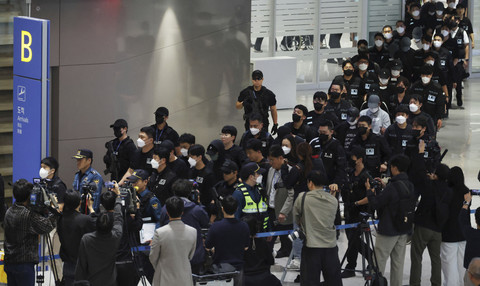 Petugas kepolisian mengawal warga Korea Selatan yang dideportasi dan ditahan oleh otoritas Kamboja atas dugaan keterlibatan dalam operasi penipuan siber setibanya di Bandara Internasional Incheon, Seoul, Korea Selatan, Sabtu (18/10/2025).  Foto: Yonhap/AFP