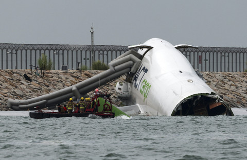 Petugas darurat melakukan pencarian korban dari pesawat kargo yang tergelincir dari landasan pacu saat mendarat di di Bandara Internasional Hong Kong, Hong Kong, Senin (20/10/2025). Foto: Tyrone Siu/Reuters