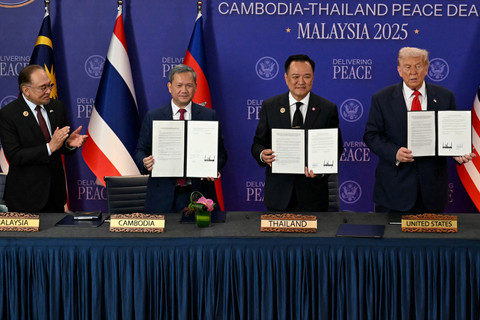 Presiden AS Donald Trump menyaksikan PM Thailand Anutin Charnvirakul dan PM Kamboja Hun Manet menunjukkan dokumen penandatanganan kesepakatan gencatan senjata di sela-sela KTT ke-47 ASEAN di Kuala Lumpur, Malaysia, Minggu (26/10/2025). Foto: Evelyn Hockstein/REUTERS