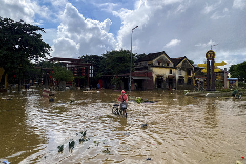Seorang warga mendorong sepeda saat banjir di Hoi An, Vietnam, Jumat (31/10/2025). Foto: Thinh Nguyen/REUTERS