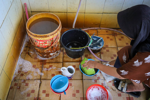 Seorang warga mencuci alat makan di Kampung Apung, Kapuk Teko, Kalideres, Jakarta Barat. Foto: Iqbal Firdaus/kumparan