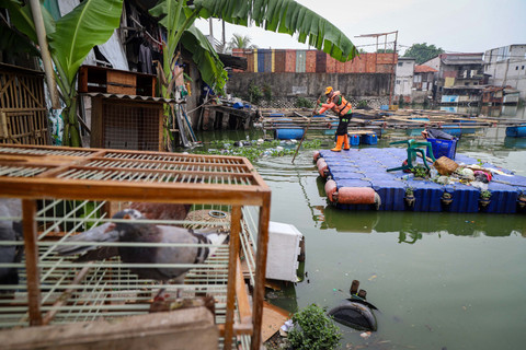 Seorang petugas PPSU membersihkan halaman yang tergenang di Kampung Apung, Kapuk Teko, Kalideres, Jakarta Barat. Foto: Iqbal Firdaus/kumparan