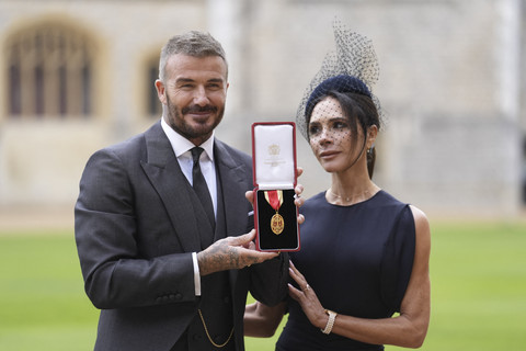 Legenda sepak bola Inggris David Beckham berpose dengan menunjukkan medali gelar bangsawan bersama istri Victoria Beckham di Kastil Windsor, Inggris, Selasa (4/11/2025).  Foto: Andrew Matthews / POOL / AFP