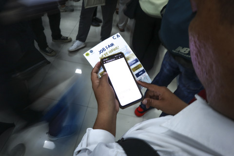 Pengemudi ojek online, Anto mencari informasi lowongan pekerjaan saat pameran bursa kerja di Universitas Negeri Jakarta, Rawamangun, Jakarta. Foto: Febria Adha Larasati/kumparan