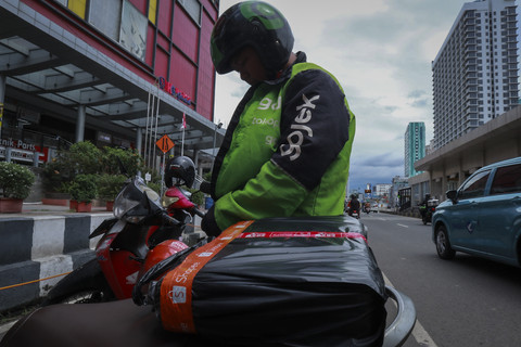 Pengemudi ojek online, Anto memakai jaket saat ingin mengantarkan paket kiriman di Mangga Dua, Jakarta Barat. Foto: Febria Adha Larasati/kumparan
