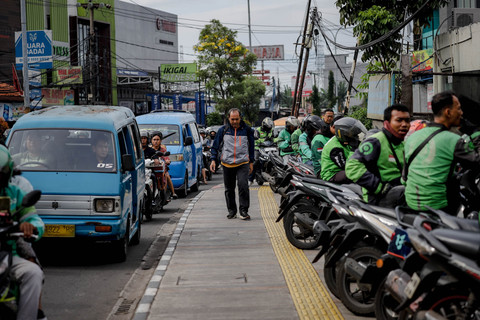 Warga berjalan saat sejumlah motor terparkir di trotoar dekat pintu timur Stasiun Depok Lama, Jalan Kartini, Depok, Jawa Barat, Kamis (13/11/2025). Foto: Jamal Ramadhan/kumparan