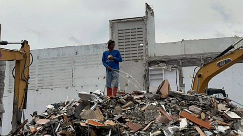 Pekerja menyiram tumpukkan puing rumah yang dibongkar milik anggota DPR, Ahmad Sahroni di Tanjung Priok, Jakarta Utara, Jumat (14/11/2025).   Foto: Abid Raihan/kumparan