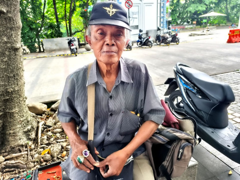 Penjual cincin batu akik, Manto (60) berada di Jalan Asia Afrika, Kota Bandung, Sabtu (15/11/2025).  Foto: Linda Lestari/kumparan