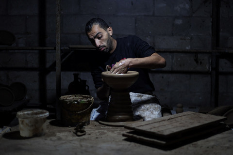 Seorang pengrajin tembikar membentuk tanah liat di sebuah bengkel di Kota Gaza, Senin (17/11/2025). Foto: Omar AL-QATTAA / AFP