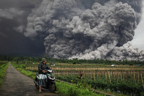 Seorang pria mengamati muntahan material vulkanik saat terjadi letusan Gunung Semeru seperti yang terlihat dari desa Sumbermujur di Lumajang, provinsi Jawa Timur, Rabu (19/11/2025). Foto: Agus Harianto/AFP