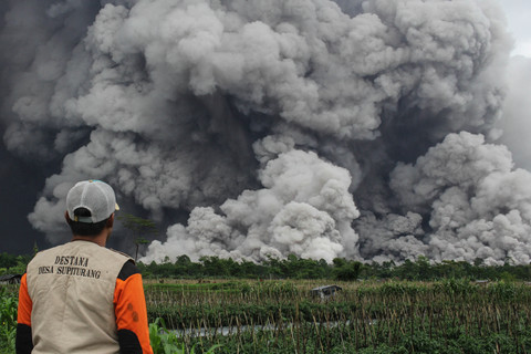 Seorang pria mengamati muntahan material vulkanik saat terjadi letusan Gunung Semeru seperti yang terlihat dari desa Sumbermujur di Lumajang, provinsi Jawa Timur, Rabu (19/11/2025). Foto: Agus Harianto/AFP