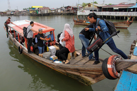 Petugas Disdukcapil Medan menaiki sampan untuk menyebrang ke Kampung Nelayan Seberang. Foto: Yudi Manar/ ANTARA FOTO