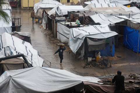 Warga Palestina berjalan melewati kamp tenda saat hujan di Khan Younis, Jalur Gaza selatan, Selasa (25/11/2025). Foto: Ramadan Abed/REUTERS