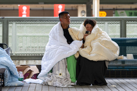 Warga beristirahat di lokasi kebakaran di Wang Fuk Court, sebuah kompleks perumahan di distrik Tai Po, Wilayah Baru Hong Kong, Kamis (27/11/2025). Foto: Chan Long Hei/AP Photo