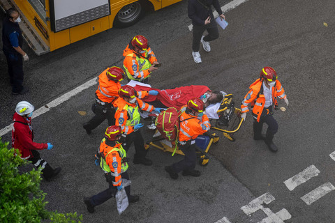 Petugas kesehatan mengevakuasi seorang perempuan dari kebakaran yang terjadi di Wang Fuk Court, sebuah kompleks perumahan di distrik Tai Po, Wilayah Baru Hong Kong, Kamis (27/11/2025). Foto: Chan Long Hei/AP Photo