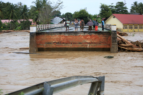 Warga menyaksikan jembatan lintas jalur nasional putus akibat diterjang banjir bandang di Desa Manyang Cut, Kecamatan Mereudu, Kabupaten Pidie, Aceh, Kamis (27/11/2025). Foto: ANTARA FOTO/Ampelsa