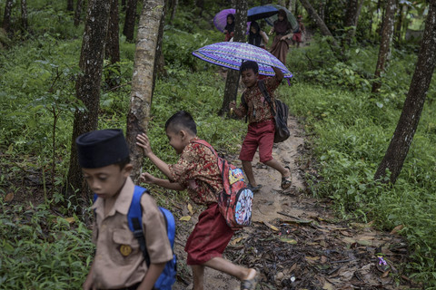 Siswa terpeleset saat berjalan melintasi hutan untuk pulang. Foto: Muhammad Bagus Khoirunas/ANTARA FOTO