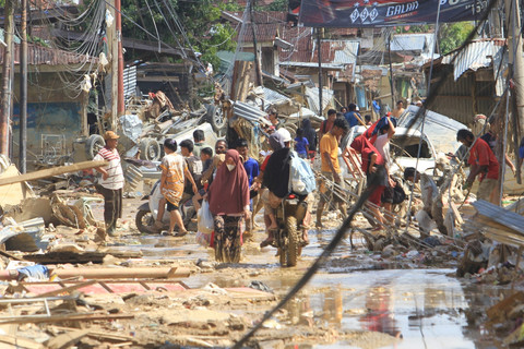Sejumlah warga melintas di dekat puing-puing yang terbawa arus banjir di kawasan Desa Bukit Tempurung, Kota Kuala Simpang, Kabupaten Aceh Tamiang, Aceh, Rabu (3/12/2025). Foto: Syifa Yulinnas/ANTARA FOTO