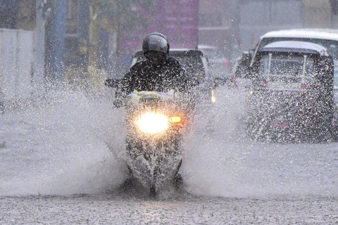 Pengendara sepeda motor melintasi jalan yang tergenang oleh air saat hujan di Colombo, Sri Lanka, Jumat (5/12/2025). Foto: Ishara S. Kodikara/AFP
