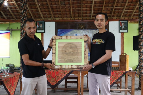 Adif Ardiansyah (kiri) menyerahkan hasil dari kegiatan pembuatan suvenir manuskrip dari daun lontar kepada Rokipiantoro, Ketua Pokdarwis Setopuro