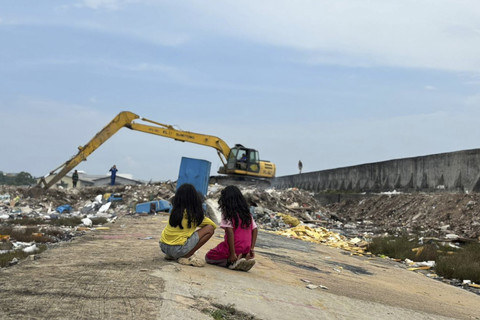 Dua bocah melihat alat berat yang dioperasikan untuk memperbaiki tanggul yang bocor di Muara Baru, Jakarta Utara, Minggu (7/12/2025).  Foto: Amira Nada Fauziyyah/kumparan