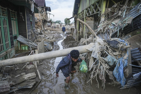 Warga merunduk melewati tiang listrik yang roboh akibat banjir bandang di Kuala Simpang, Kabupaten Aceh Tamiang, Aceh, Sabtu (6/12/2025). Foto: Erlangga Bregas Prakoso/ANTARA FOTO