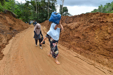 Penyintas bencana melewati jalan bekas longsor yang telah dibersihkan di Jorong Silungkang, Agam, Sumatera Barat, Minggu (7/12/2025). Foto: Wahdi Septiawan/ANTARA FOTO
