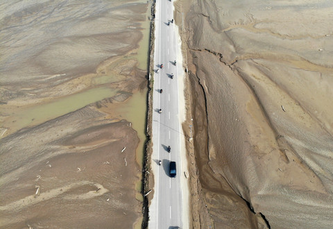 Kendaraan melintas di jalan yang berada di antara lahan pertanian yang rusak akibat terendam banjir dan lumpur banjir bandang di Pidie Jaya, Aceh, Senin (8/12/2025). Foto: Irwansyah Putra/ANTARA FOTO