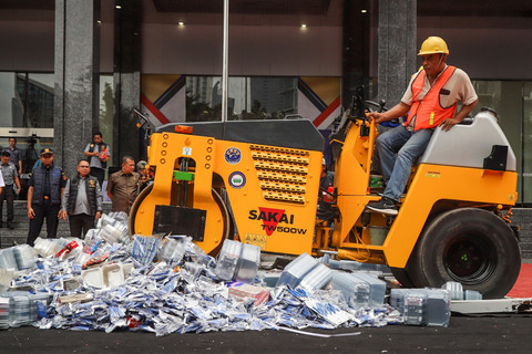 Petugas dengan menggunakan alat berat memusnahkan barang bukti hasil pelanggaran kekayaan intelektual di Kantor Kemenkumham RI, Jakarta, Selasa (9/12/2025). Foto: Iqbal Firdaus/kumparan