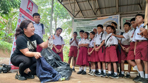 Pengurus Bank Sampah Induk Likupang, Yudith Rondonuwu, saat memberikan penjelasan tentang pemilahan sampah kepada anak-anak SD Negeri Sarawet, Minahasa Utara, dalam program Kampung Merdeka yang digelar oleh Alfamidi Branch Manado.