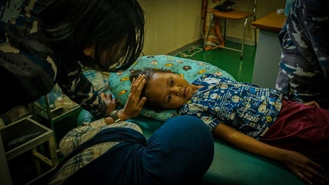 Anggota TNI menghibur anak korban bencana alam yang dievakuasi dari Dusun Kuala Pusung Kapal, Aceh Tamiang, yang alami patah tulang. Foto: Dok. TNI AL