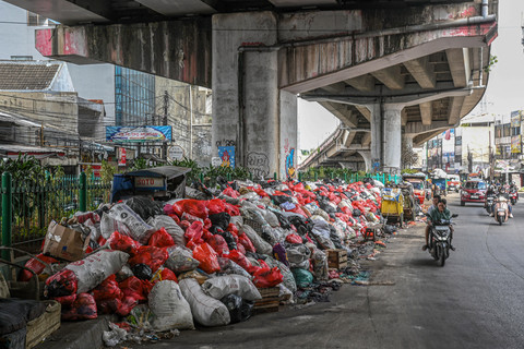 Pengendara sepeda motor melintas di dekat tumpukan sampah di Jalan Dewi Sartika, Ciputat, Tangerang Selatan, Banten, Sabtu (13/12/2025). Foto: ANTARA FOTO/Sulthony Hasanuddin